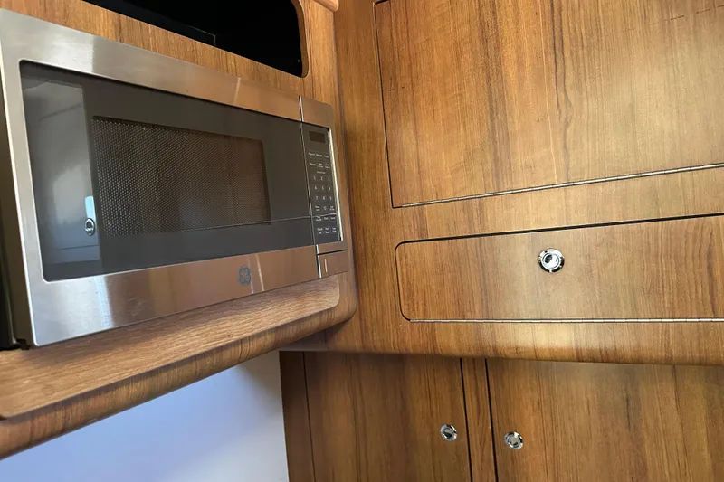 Slide: The Image of Microwave and wooden cabinetry inside a 2018 Invincible 42 model boat kitchen. - 16