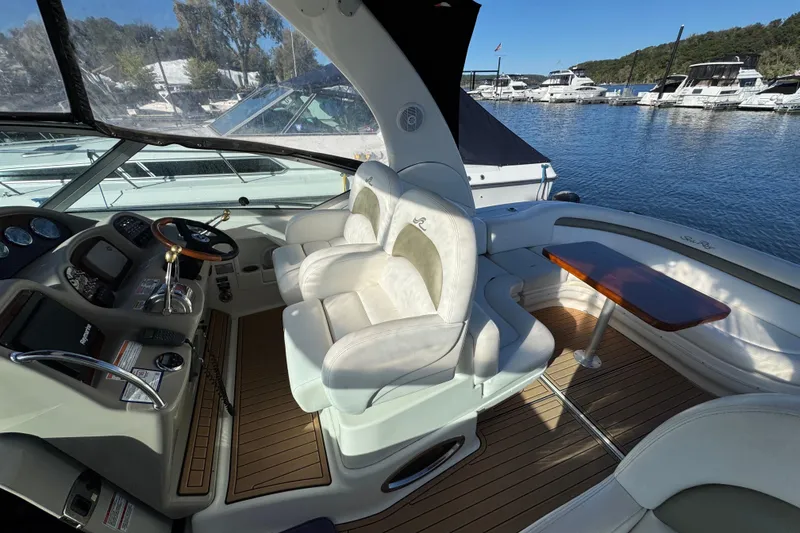 Slide: The Image of 2007 Sea Ray 340 Sundancer cockpit with plush seating and wooden table, docked at marina. - 13