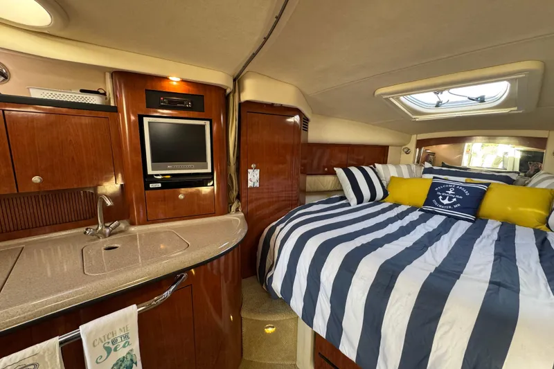 Slide: The Image of Interior of 2007 Sea Ray 340 Sundancer with cozy bed, striped bedding, and compact kitchenette. - 24