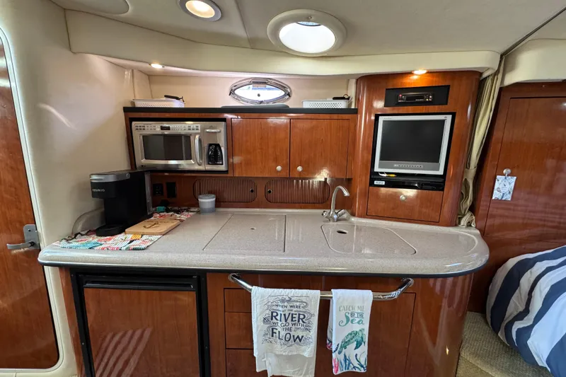Slide: The Image of 2007 Sea Ray 340 Sundancer interior kitchen with microwave, sink, and TV. - 25