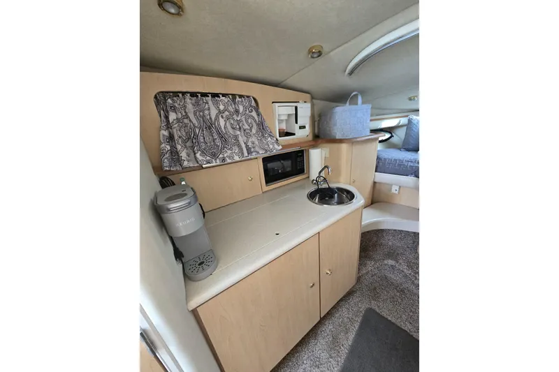 Slide: The Image of 1998 Regal Commodore 3060 cabin interior with kitchenette, sink, and cozy sleeping area. - 11