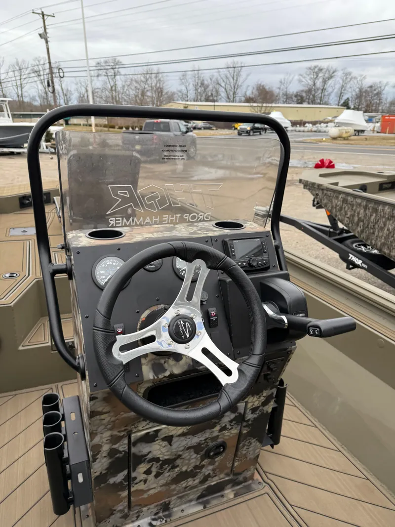 Slide: The Image of 2025 Thor 1900 boat console with steering wheel and controls, parked outdoors. - 5
