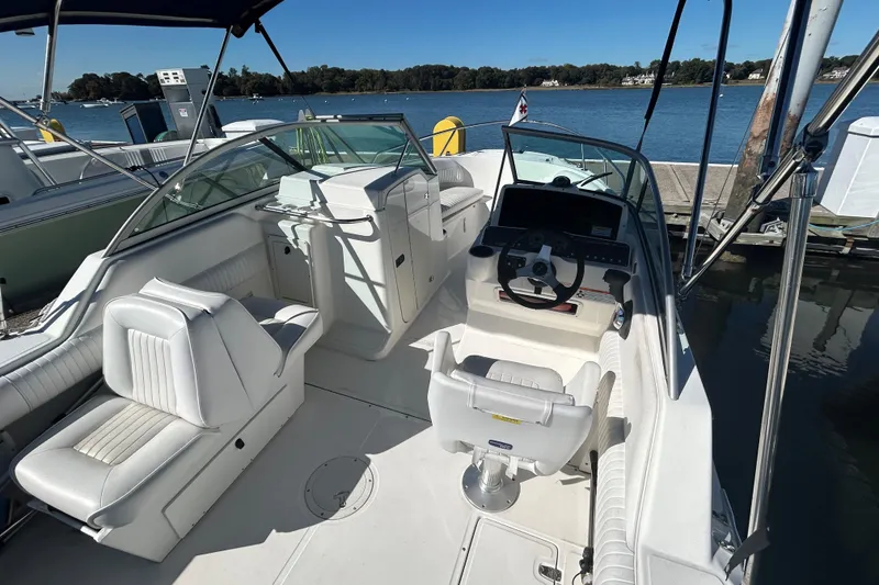 Slide: The Image of 2006 Boston Whaler 210 Ventura boat interior with seating and steering wheel, docked by the water. - 10