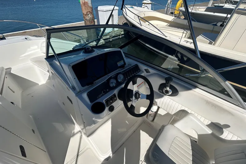 Slide: The Image of 2006 Boston Whaler 210 Ventura boat interior with steering wheel and dashboard, docked by the water. - 12