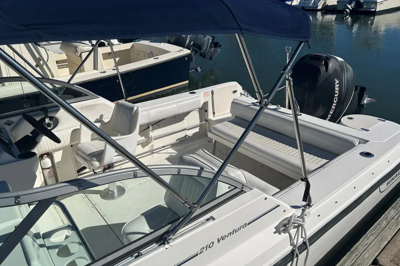 Slide: The Image of 2006 Boston Whaler 210 Ventura boat docked, featuring seating and Mercury outboard motor. - 7