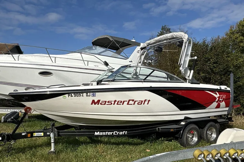 The Image of 2012 MasterCraft X-15 boat on trailer, parked outdoors under blue sky. - 1