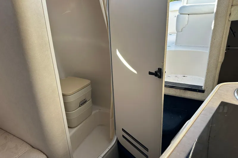 Slide: The Image of 2001 Sea Ray 240 Sundancer cabin with compact marine toilet and open door. - 13