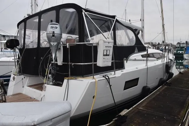 Slide: The Image of 2016 Jeanneau 54 yacht docked, featuring a covered cockpit and outboard motor. - 11