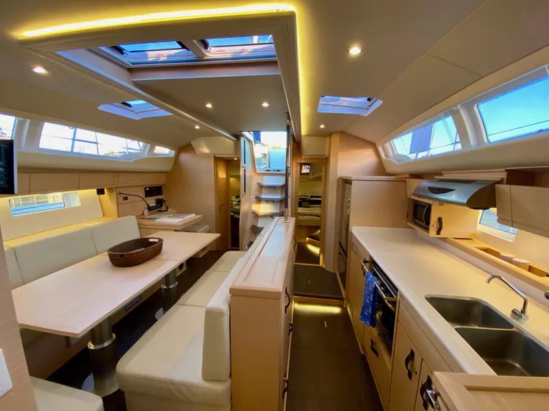 Slide: The Image of Luxurious interior of a 2016 Jeanneau 54 yacht, featuring modern kitchen and dining area. - 18