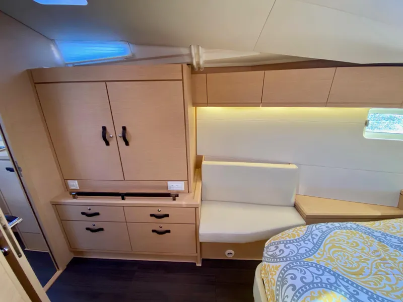 Slide: The Image of Interior of 2016 Jeanneau 54 yacht cabin with wood cabinetry and cozy seating area. - 38