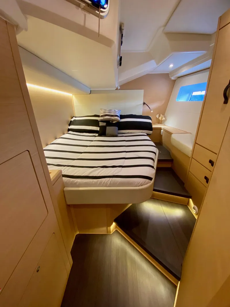 Slide: The Image of Luxurious cabin interior of 2016 Jeanneau 54 yacht with striped bedding and ambient lighting. - 44