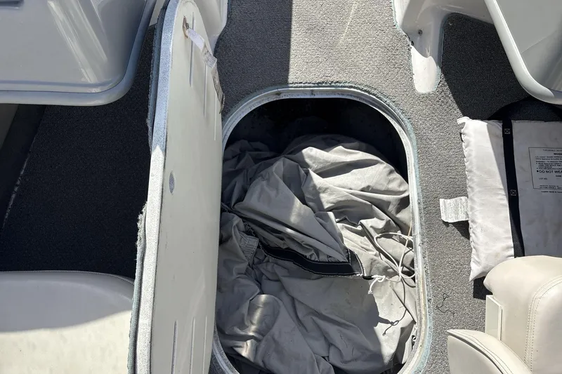 Slide: The Image of Open storage compartment in 2001 Four Winns 180 Horizon boat, containing a folded cover. - 13