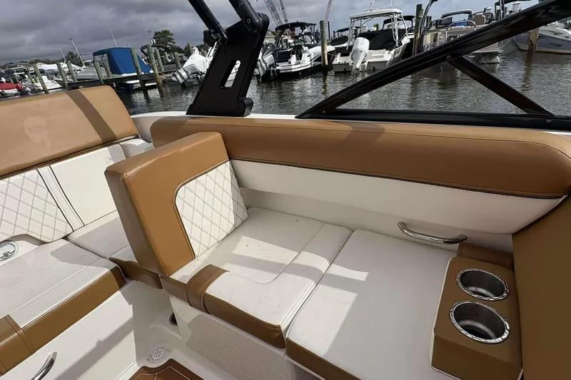Slide: The Image of 2021 Bayliner DX 2000 boat interior with tan and white seating, cup holders, docked at marina. - 11