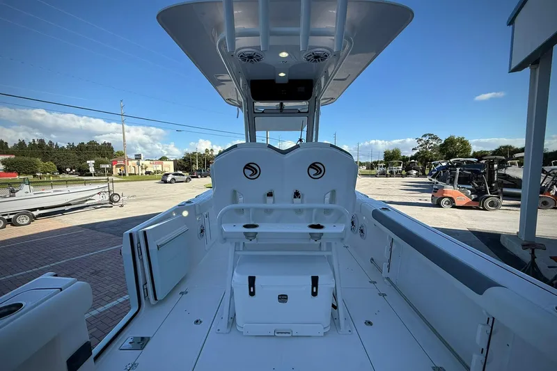 Slide: The Image of 2026 Edgewater 250CC boat interior with seating and storage, parked outdoors under clear sky. - 13