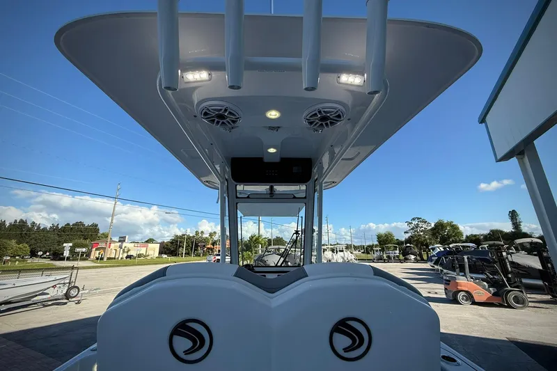 Slide: The Image of 2026 Edgewater 250CC boat with T-top and speakers, parked outdoors under blue sky. - 21