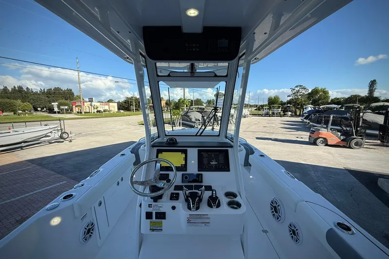 Slide: The Image of 2026 Edgewater 250CC boat cockpit with modern controls and steering wheel, parked outdoors. - 22