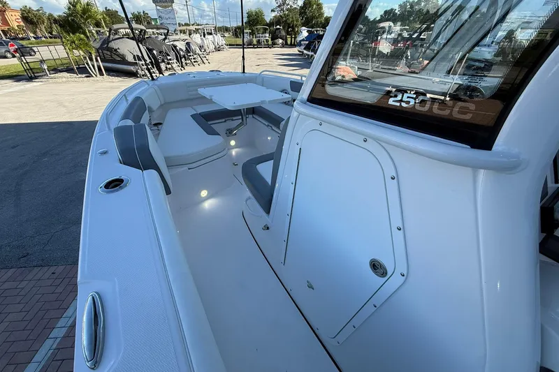 Slide: The Image of 2026 Edgewater 250CC boat interior with seating and table, docked outdoors. - 28