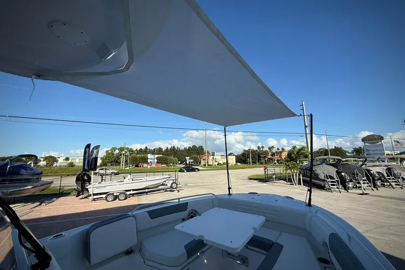 Slide: The Image of 2026 Edgewater 250CC boat with sunshade, parked in a marina under clear blue sky. - 34