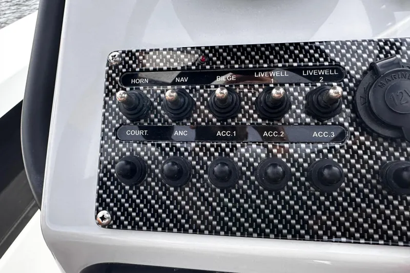 Slide: The Image of Control panel of a 2022 Maverick 17 HPX-V boat with various switches and carbon fiber finish. - 18