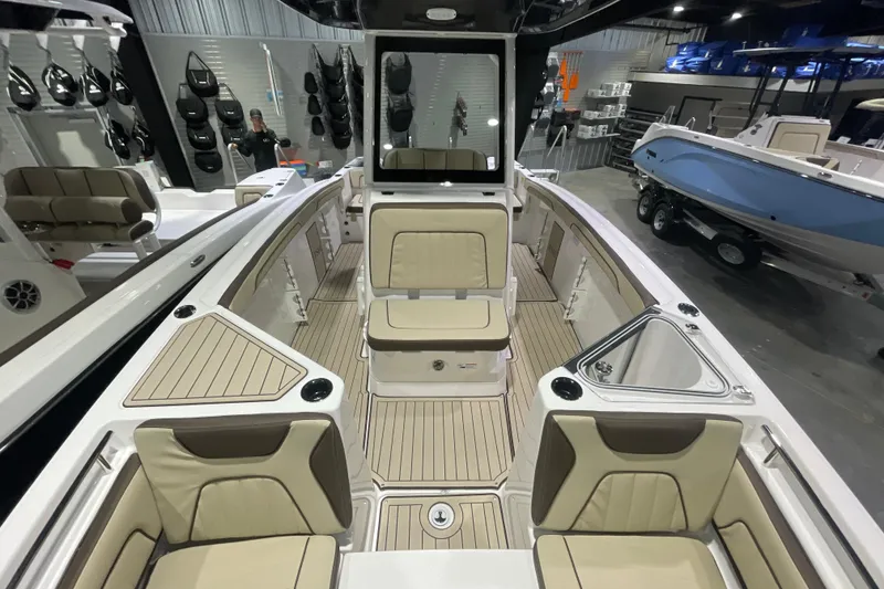 Slide: The Image of 2025 Yamaha Boats 252 FSH Sport interior with beige seating and sleek design in showroom. - 10