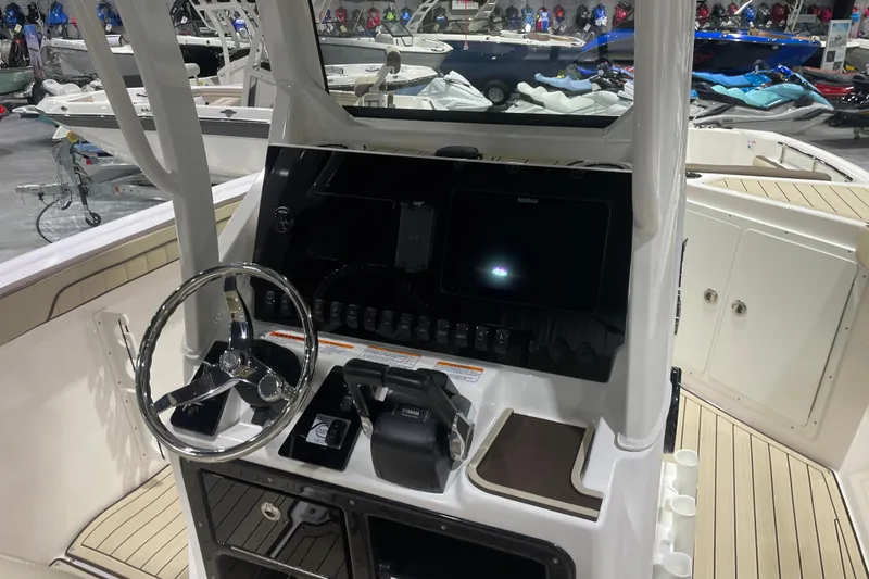 Slide: The Image of 2025 Yamaha Boats 252 FSH Sport dashboard with steering wheel and controls in showroom. - 6