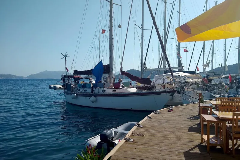 Slide: The Image of Sailboat Tayana Vancouver 42, 1988 model, docked at a sunny marina with wooden deck. - 11