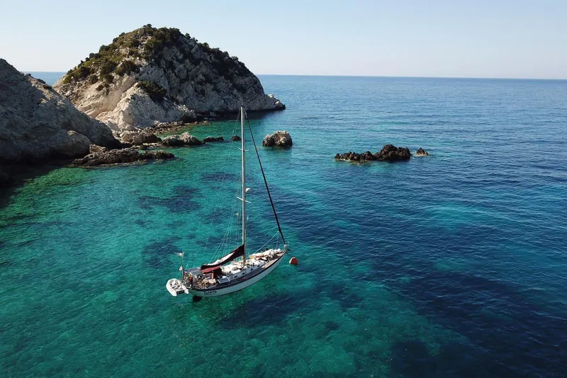 Slide: The Image of Sailboat Tayana Vancouver 42, 1988, anchored in clear turquoise waters near rocky island. - 4