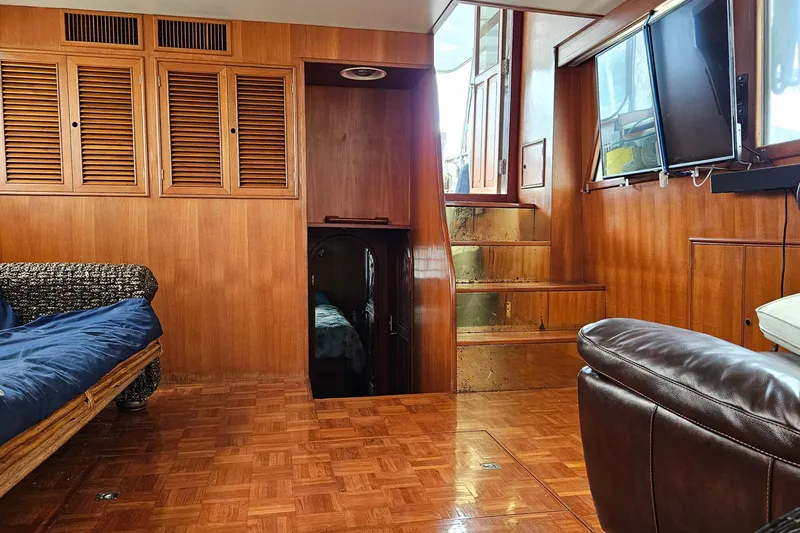 Slide: The Image of Interior of 1985 CHB 48 Motor Yacht with wood paneling, stairs, and seating area. - 45