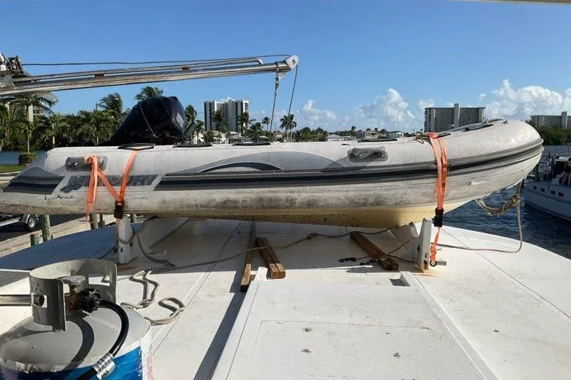 Slide: The Image of 1985 CHB 48 Motor Yacht with inflatable boat on deck, docked near palm trees and buildings. - 7