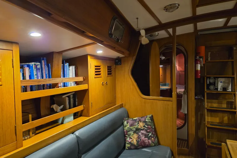 Slide: The Image of Interior of 1986 Cambria 46 yacht with wooden cabinetry, bookshelves, and cozy seating area. - 18