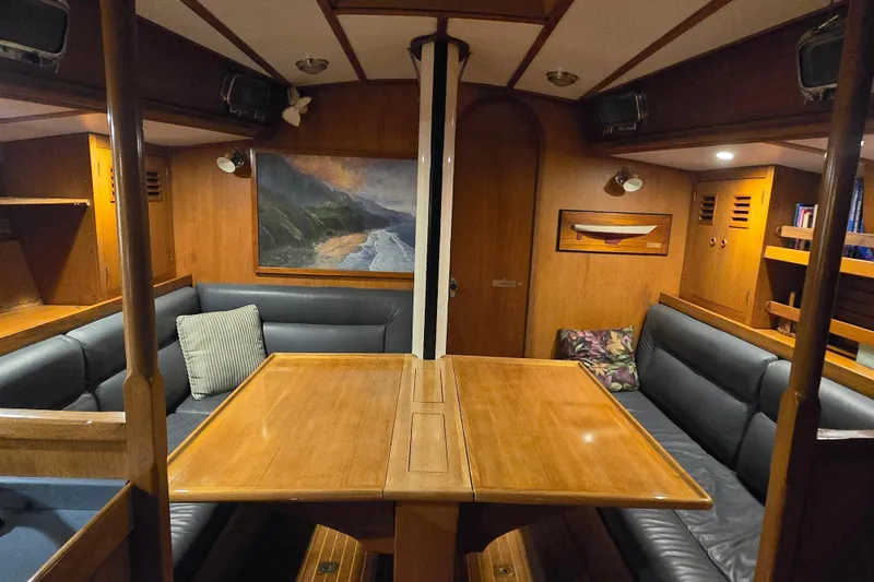 Slide: The Image of Interior of 1986 Cambria 46 yacht with wooden table, blue seating, and coastal artwork. - 23