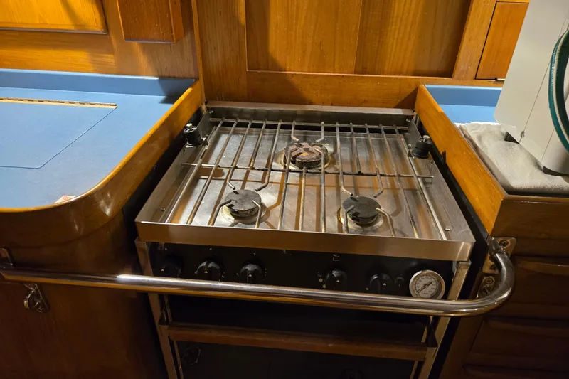 Slide: The Image of 1986 Cambria 46 yacht kitchen with a two-burner stove and wooden cabinetry. - 33