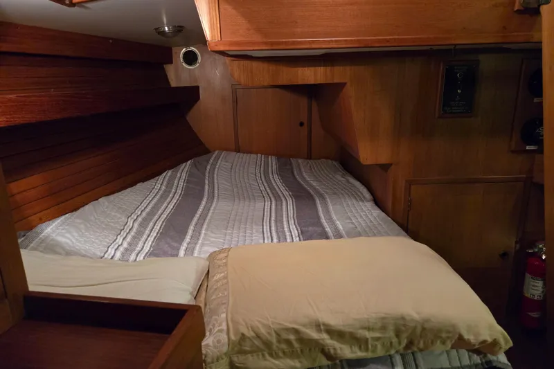 Slide: The Image of Cozy cabin interior of 1986 Cambria 46 sailboat with wooden paneling and striped bedding. - 36