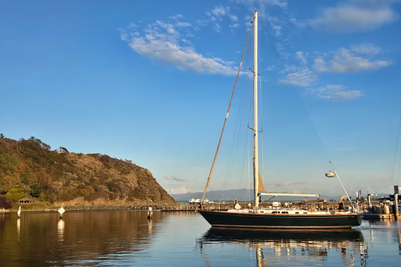 Slide: The Image of Sailboat Cambria 46 (1986) docked in serene harbor with clear blue sky. - 5