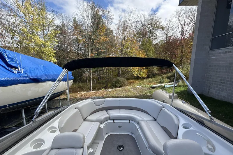 Slide: The Image of 2002 Regal 2400 Bowrider boat with seating, bimini top, and autumn trees in the background. - 14