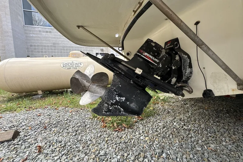 Slide: The Image of 2002 Regal 2400 Bowrider boat with Mercury outboard motor, parked on gravel. - 3