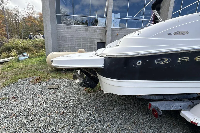 Slide: The Image of 2002 Regal 2400 Bowrider boat on gravel near a modern building. - 5