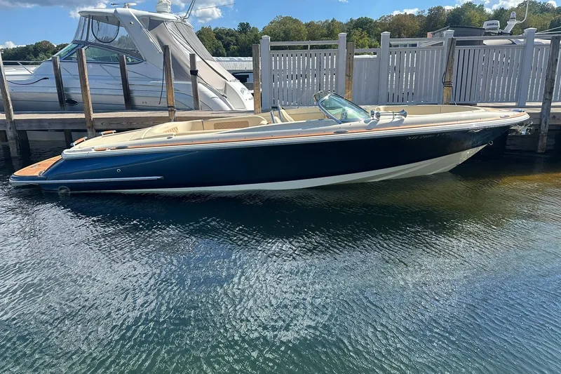 Slide: The Image of 2018 Chris-Craft Launch 27 boat docked in calm waters, showcasing sleek design. - 0