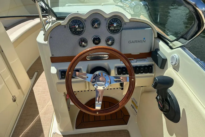 Slide: The Image of 2018 Chris-Craft Launch 27 boat dashboard with wooden steering wheel and Garmin navigation system. - 12