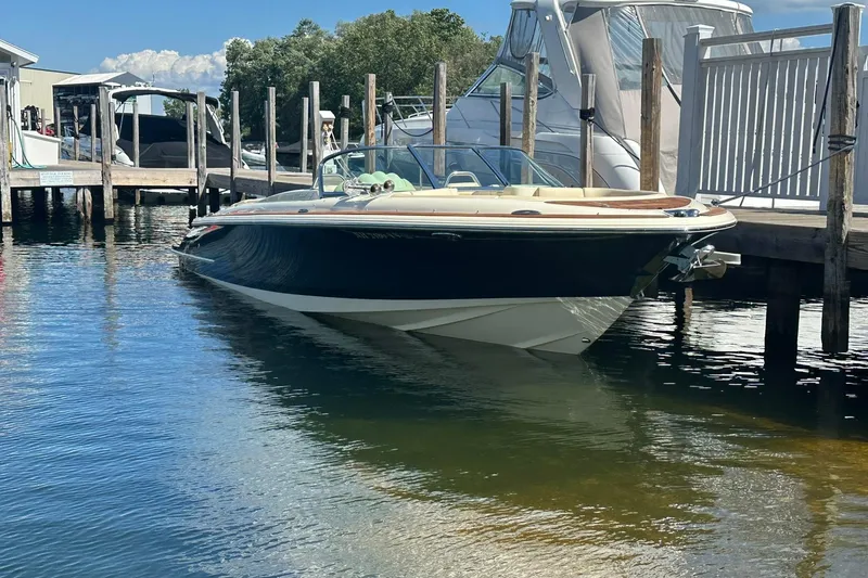 Slide: The Image of 2018 Chris-Craft Launch 27 boat docked in a marina, reflecting on calm water. - 2