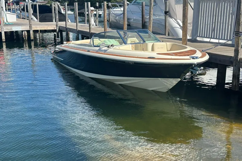 Slide: The Image of 2018 Chris-Craft Launch 27 boat docked in a marina, reflecting on calm water. - 3