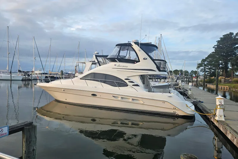 The Image of 2007 Sea Ray 44 Sedan Bridge yacht docked at a marina, surrounded by sailboats. - 0