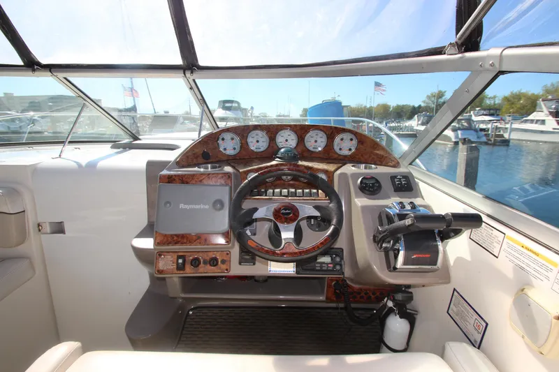 Slide: The Image of 2006 Rinker 320 Express Cruiser helm with steering wheel and control panel, docked at marina. - 11