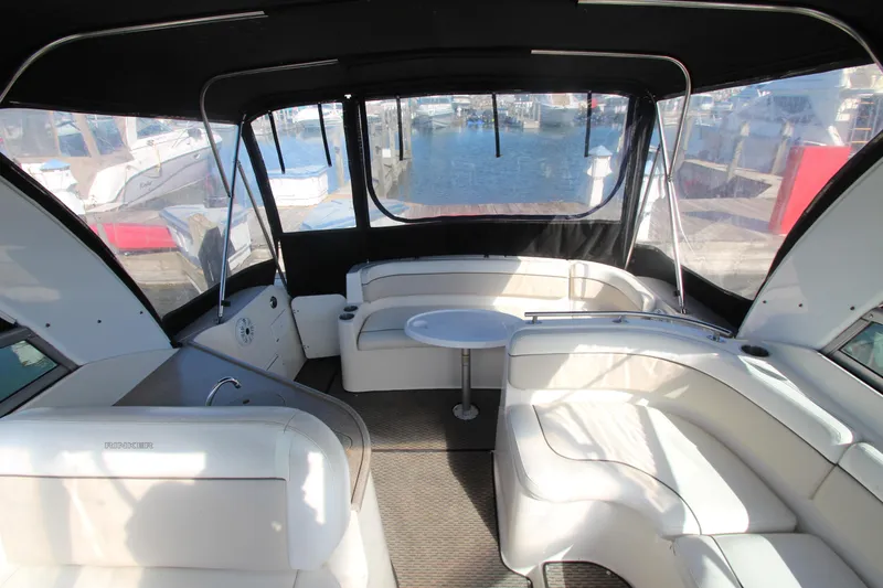 Slide: The Image of 2006 Rinker 320 Express Cruiser interior with white seating and table, docked at marina. - 16