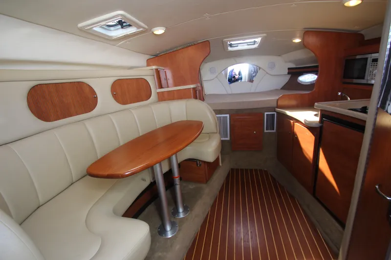 Slide: The Image of 2006 Rinker 320 Express Cruiser interior with dining area, kitchenette, and cozy sleeping space. - 21
