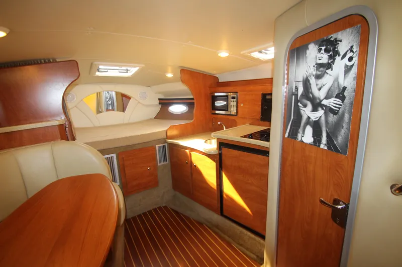 Slide: The Image of 2006 Rinker 320 Express Cruiser interior with kitchenette, seating, and cozy sleeping area. - 24