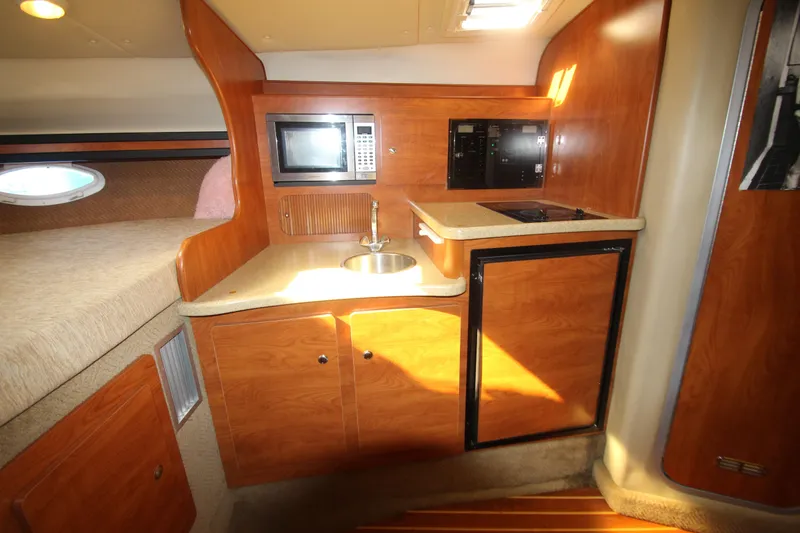 Slide: The Image of 2006 Rinker 320 Express Cruiser interior with kitchenette, microwave, sink, and wood cabinetry. - 28