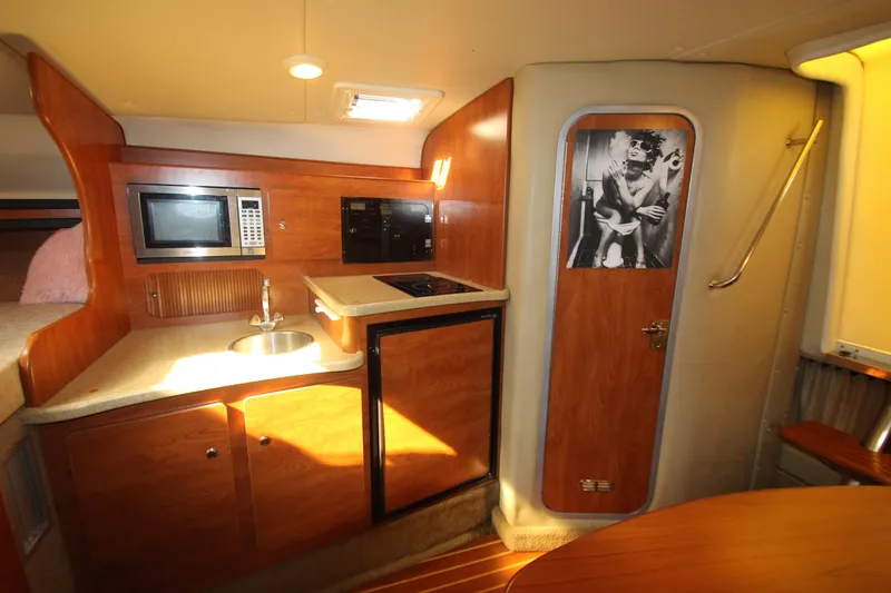 Slide: The Image of 2006 Rinker 320 Express Cruiser interior with kitchenette, microwave, and stylish wood finish. - 29