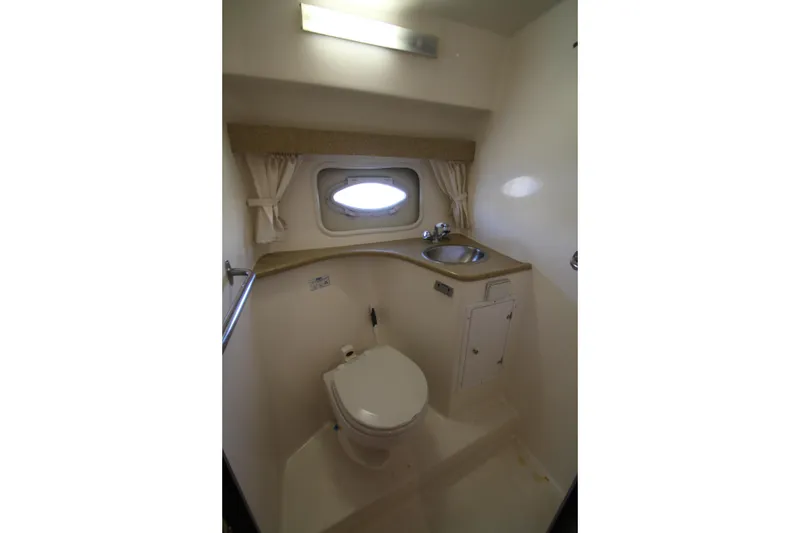 Slide: The Image of 2006 Rinker 320 Express Cruiser bathroom with toilet, sink, and porthole window. - 36
