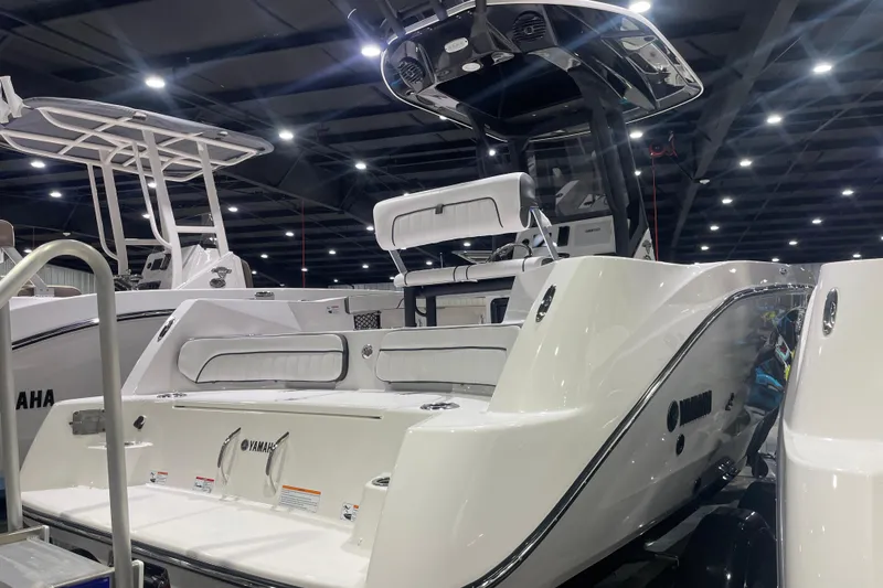 Slide: The Image of 2025 Yamaha Boats 222 FSH Sport E displayed indoors, showcasing sleek design and seating. - 2